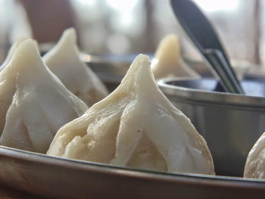 A close-up of freshly steamed white modaks, the sweet dumpling offering associated with Ganesha.