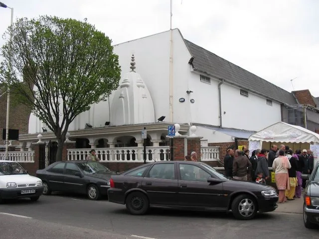 The white domed exterior of the Vishwa Temple in Southall, London, with visitors gathered outside.