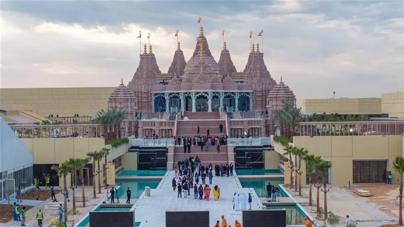 The pink sandstone spires of the BAPS Hindu Mandir in Abu Dhabi, with devotees gathered on its steps.