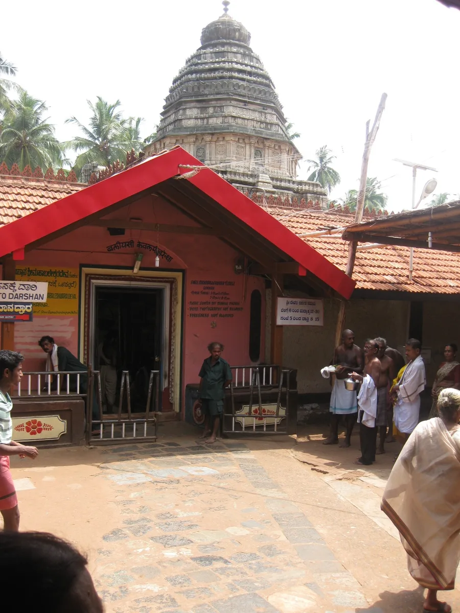 The red-roofed entrance courtyard of the Mahabaleshwar Temple at Gokarna, with its carved stone tower behind.